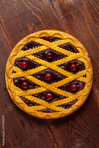 Cherry shortcrust pastry pie decorated with cherries and pastry grill.