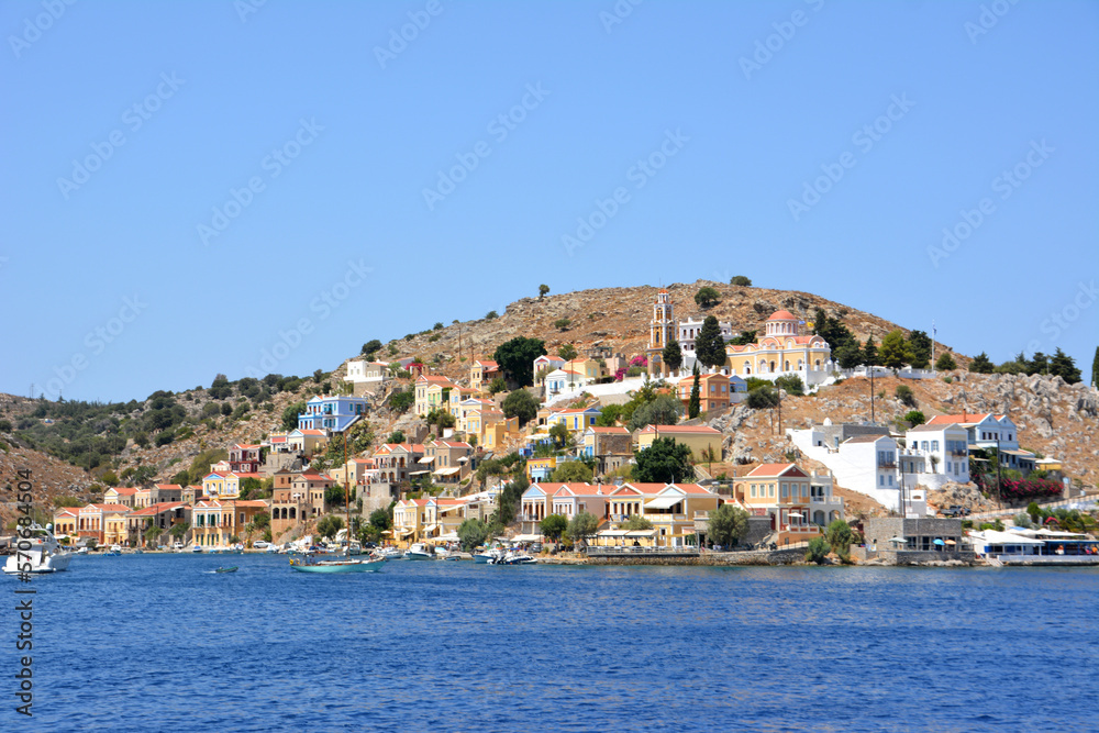 greek island Symi with multicolored buildings, monastery and waterfront with blue sea