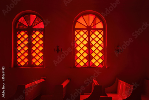 Vintage stained glass window in red wall in church. Interior design concept.