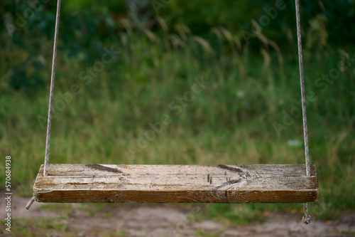Wooden swing hanging on a rope in a park. Selective focus.