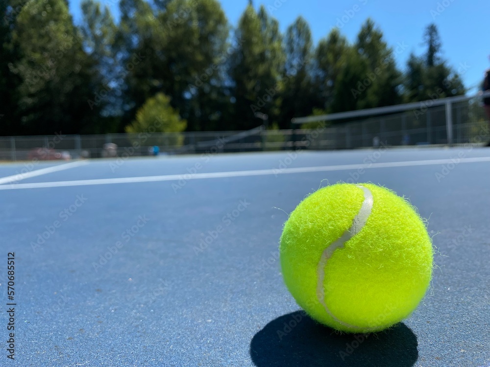 Bright tennis ball in closeup on tennis court in spring time