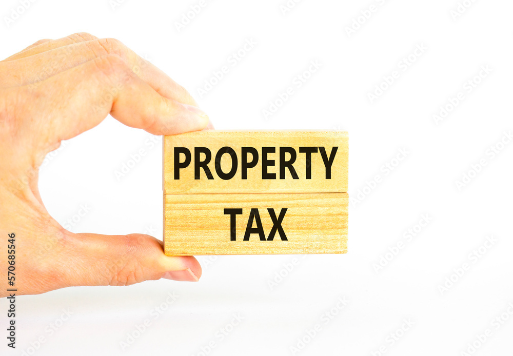 Property tax symbol. Concept words Property tax on wooden blocks. Beautiful white table white background. Businessman hand. Business and property tax concept. Copy space. Property tax symbol. Concept words Property tax on wooden blocks. Beautiful white table white background. Businessman hand. Business and property tax concept. Copy space.