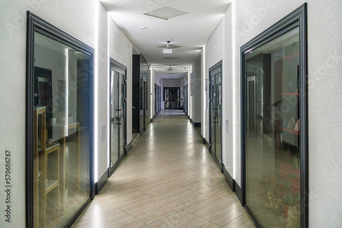 A corridor in an urban-type office building. Modern interior of the lobby of an office building with glass doors and clean white walls. A lighted long corridor in a modern business center.