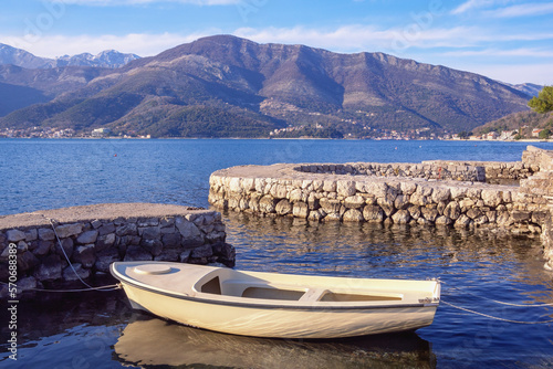Beautiful winter Mediterranean landscape. White fishing boat in small stone jetty.  Montenegro  Kotor Bay