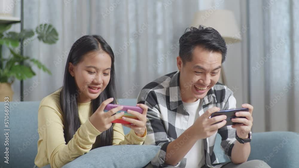 Close Up Of Asian Father And A Daughter Playing Game Together On The Smartphones While Sitting On A Sofa In The Living Room
Close Up Of Asian Father And A Daughter Playing Game Together On The Smartphones While Sitting On A Sofa In The Living Room