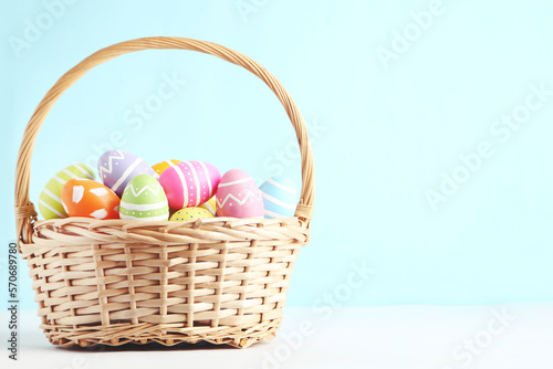 Colorful easter eggs in basket on blue background photo