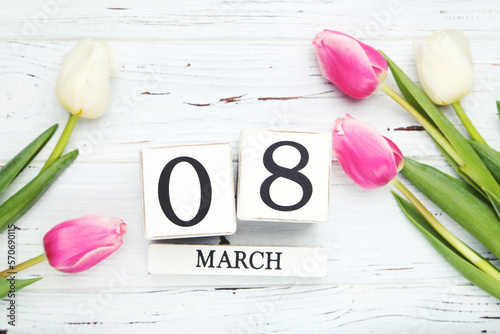 Flowers of tulips and cube calendar on white wooden background