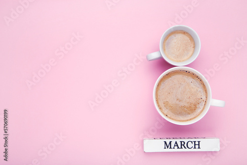 Two cups of coffee in shape 8 March on pink background