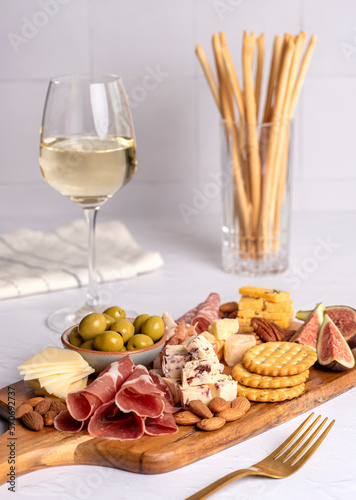 Food photography of appetizer  white wine  salami  grissini  cracker  cheese  fig  parmesan  prosciutto  cheddar  olive  almond