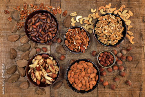 Bowls with nuts, chestnuts, almonds and hazelnuts on wooden table