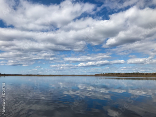 Spring landscape with blue sky and reflection of trees in the lake. Tourism and travel concept.