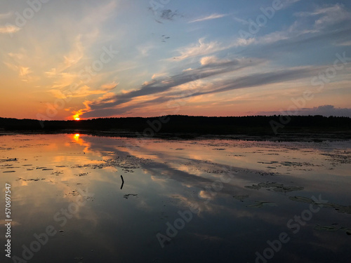 Sunset on a lake with blue skies and clouds reflecting in the water. Tourism and travel concept.