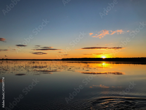 Sunset on a lake with blue skies and clouds reflecting in the water. Tourism and travel concept.