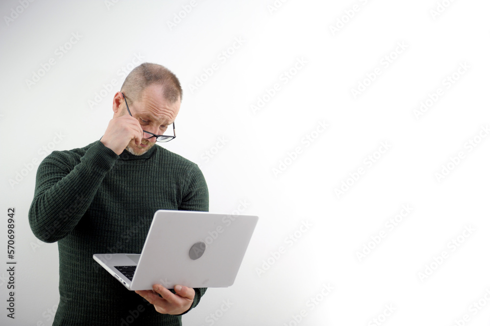 adult man lifted glasses to marshal looking at laptop he does not believe eyes interest inquisitiveness buying selling online white background space for text advertising bad eyesight ophthalmologist adult man lifted glasses to marshal looking at laptop he does not believe eyes interest inquisitiveness buying selling online white background space for text advertising bad eyesight ophthalmologist