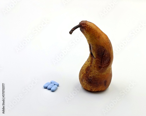 A very ripe pear next to medicines or blue pills. Concept of erection problems, impotence or erectile dysfunction  photo