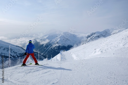 Colorful silhouettes of skiers on slope of Kasprowy Wierch Peak in Tatras Mountains. Tatra National Park, Poland