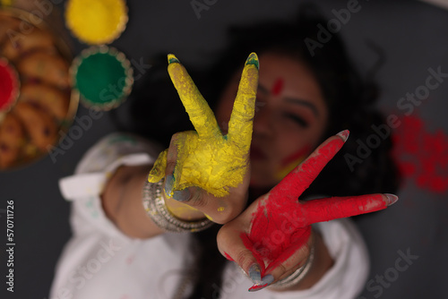 A beautiful woman girl lady laying down posing for the celebration of Holi festival of colors looking away from the camera with Abeer gulal dry color powder and Indian sweet Gujiya pedukiya kashew photo