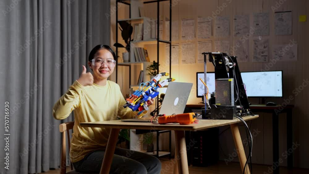 Smiling Teen Asian Girl With A Cyborg Hand Showing Thumbs Up Gesture To The Camera While Working On A Laptop At Home
Smiling Teen Asian Girl With A Cyborg Hand Showing Thumbs Up Gesture To The Camera While Working On A Laptop At Home