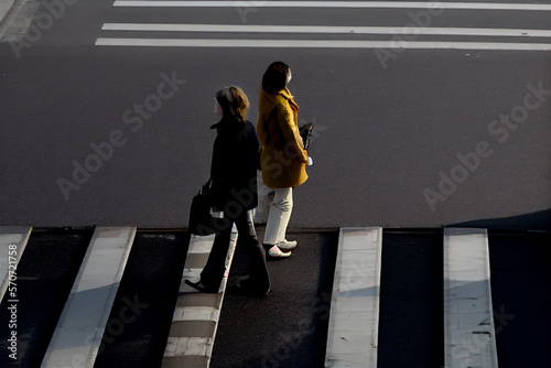 two women walk in opposite directions across the zebra crossing