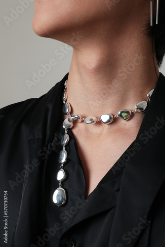 Close-up of young man wearing silver necklace posing indoor. Vertical mock-up. © face_reader_img