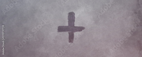 Cross made from ashes. Symbolic of Ash Wednesday. On vintage gray background.