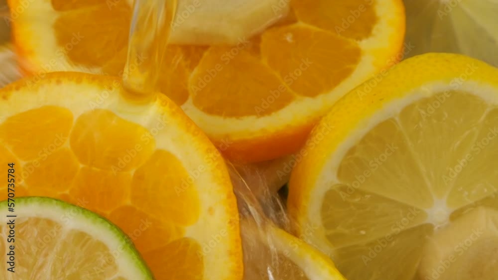 Cooking lemonade from citrus, lemon, orange, lime and ginger. Hot water is poured into a glass container. Slow motion.