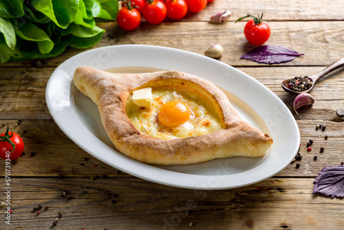 ajara Khachapuri with cheese, egg and butter, georgian kitchen on wooden table side view photo