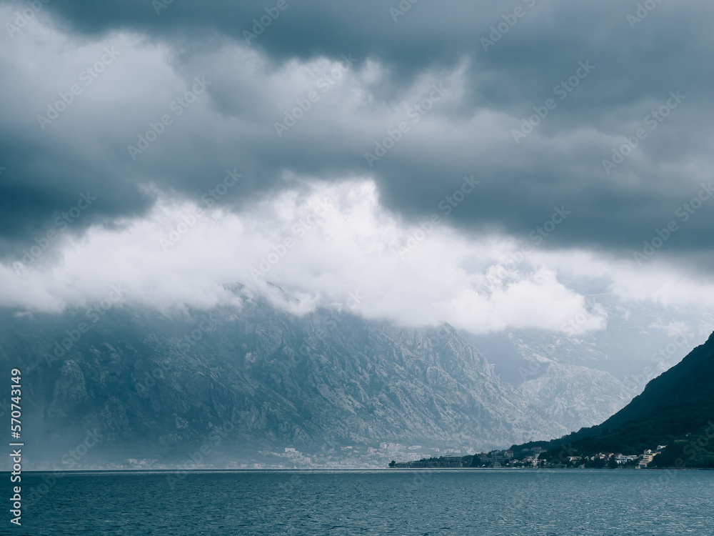 Dark stormy sky over the sea and fog in the mountains