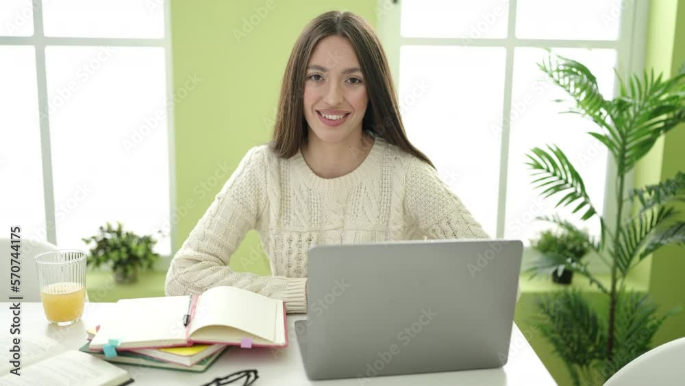 Young beautiful hispanic woman student smiling confident using laptop studying at home