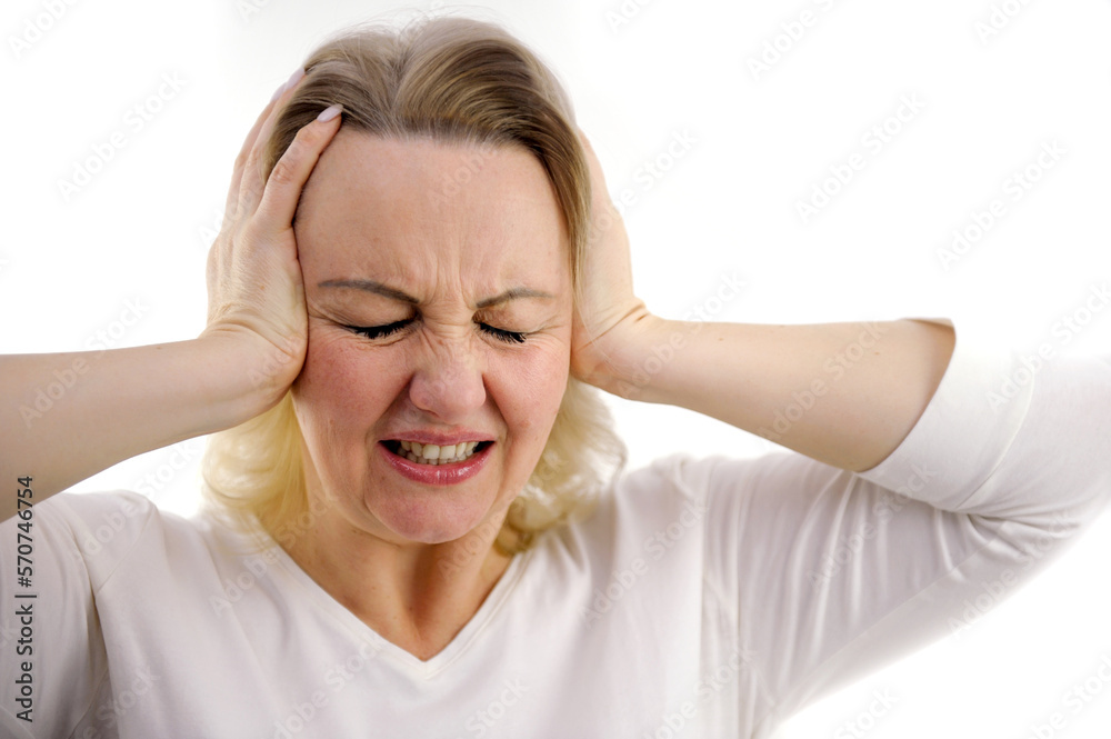 Frowning gray haired blonde woman 40 years old looks closes her ears with her hands does not want to listen studio portrait covers ears from loud noise copy space Frowning gray haired blonde woman 40 years old looks closes her ears with her hands does not want to listen studio portrait covers ears from loud noise copy space