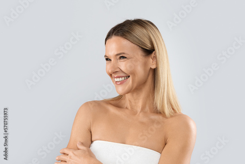 Cheery blonde woman looking at copy space, isolated on grey