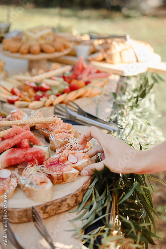 Gros plan de main détail qui choisis une tartine de saumon sur une grazing table plancha de dégustation de tapas  photo