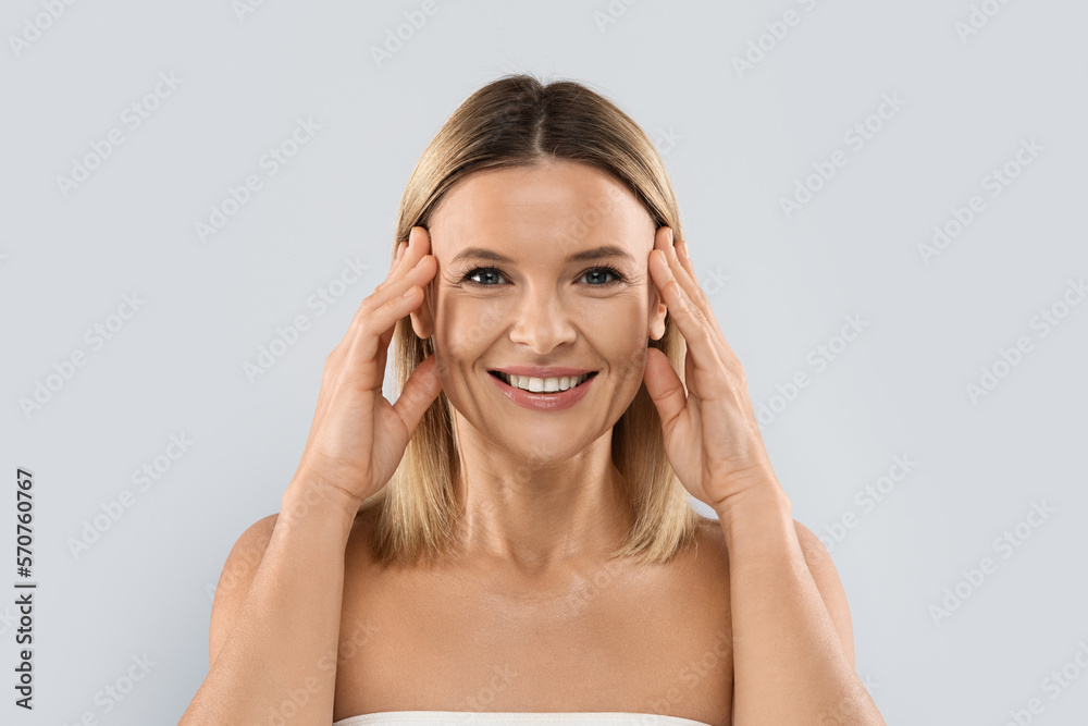 Portrait of pretty middle aged blonde woman touching her face Portrait of pretty middle aged blonde woman touching her face