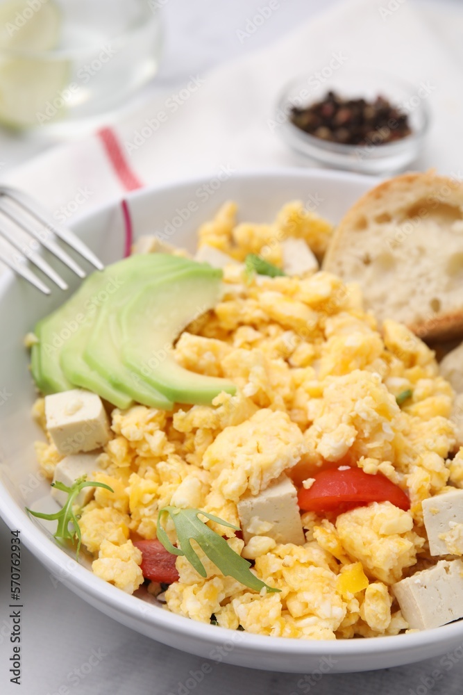 Bowl with delicious scrambled eggs, tofu and avocado on white table, closeup Bowl with delicious scrambled eggs, tofu and avocado on white table, closeup