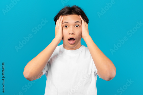 Shocked Asian Teen Boy Touching Head Posing On Blue Background