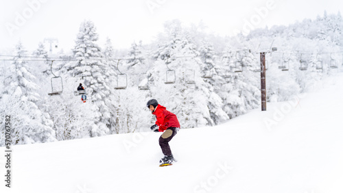 Young Asian woman practicing snowboard on snowy mountain slope at ski resort. Attractive girl enjoy outdoor active lifestyle extreme sport training freeride snowboarding on winter holiday vacation.