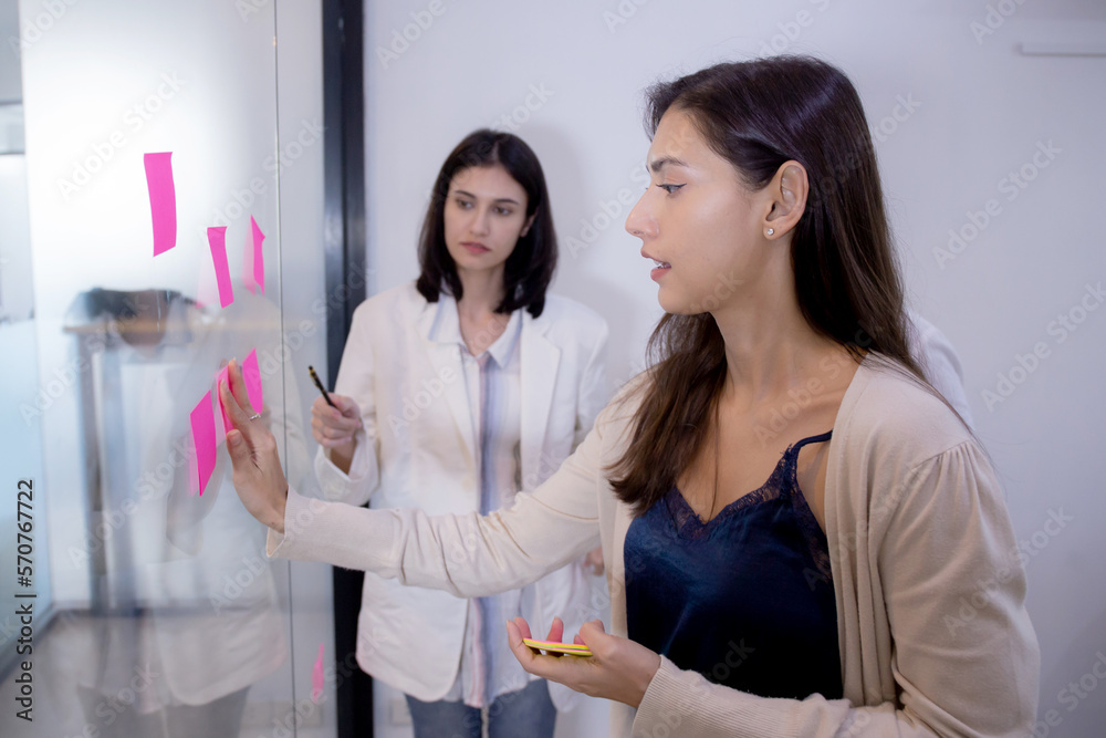 Group of team business people brainstorming and meeting for planning with sticky notes or post it on glass about marketing in the office, idea and thinking with inspiration, teamwork concept. Group of team business people brainstorming and meeting for planning with sticky notes or post it on glass about marketing in the office, idea and thinking with inspiration, teamwork concept.
