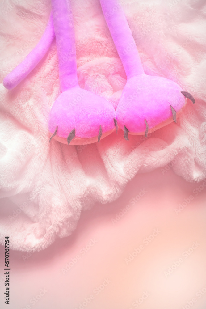 Relax concept. Pink toys soft legs on fluffy white plaid or blanket. Happy holiday and bedding. Copy space. Vertical Relax concept. Pink toys soft legs on fluffy white plaid or blanket. Happy holiday and bedding. Copy space. Vertical