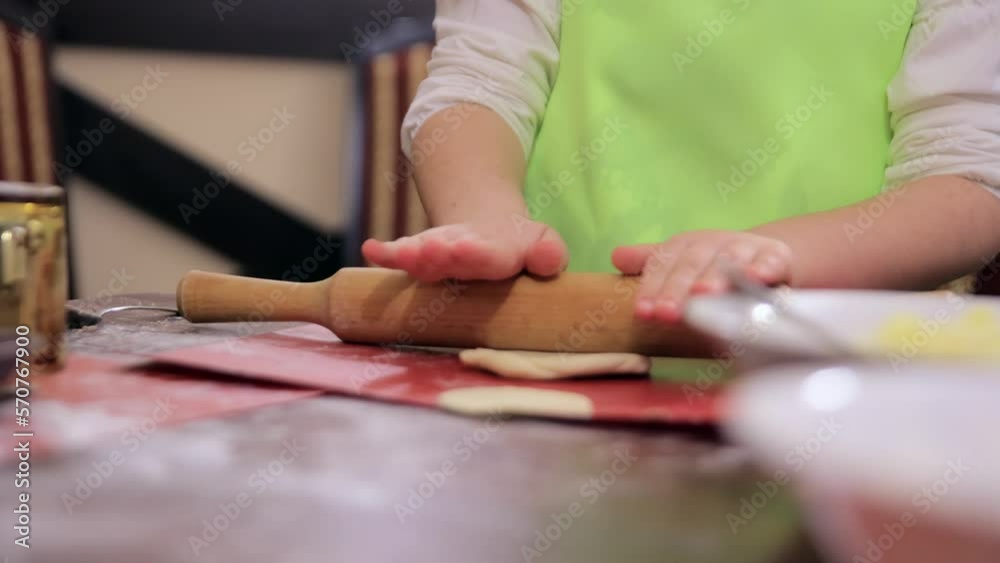 child's hands roll out the dough on the table. children's hands energetically prepare blanks for ravioli. in the frame only hands child's hands roll out the dough on the table. children's hands energetically prepare blanks for ravioli. in the frame only hands