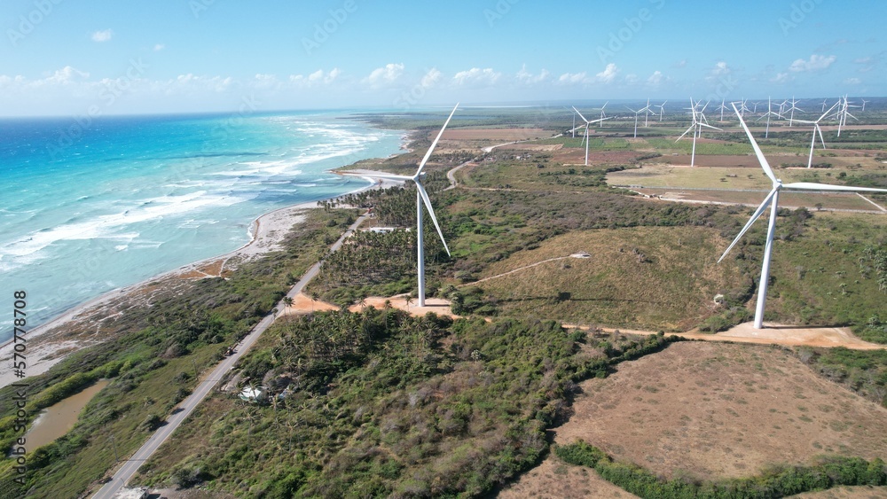 Wind farm shot next to caribbean beach from drone
