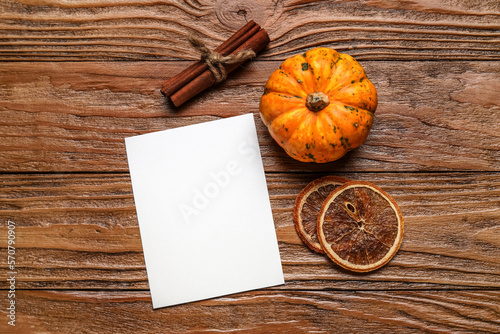 Paper sheet, cinnamon, pumpkin and dried orange slices on wooden background