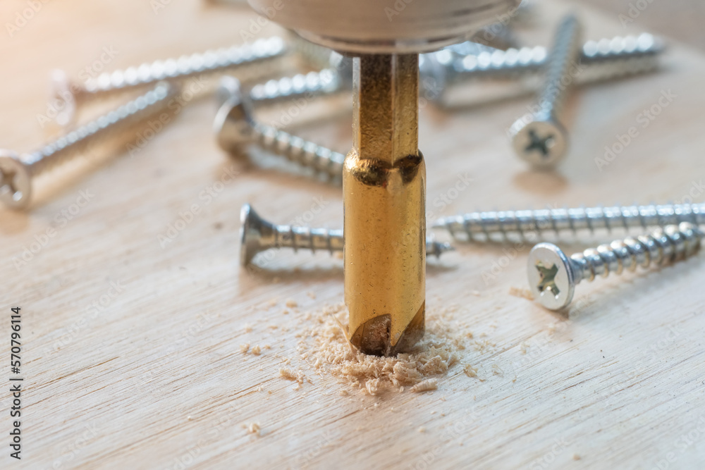 Carpenter use countersink bit to drill both a pilot hole and use countersink bit to recess the head of the screw into wood plank. DIY maker and woodworking concept. selective focus