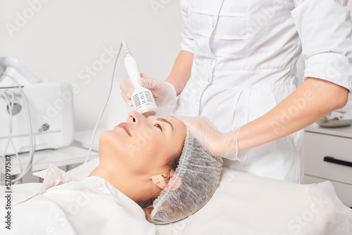 Cosmetologist makes cryotherapy for rejuvenation woman face, anti aging cosmetic procedure with in beauty spa salon. Beautician makes cryo therapy lifting with for skin rejuvenation and smoothing photo