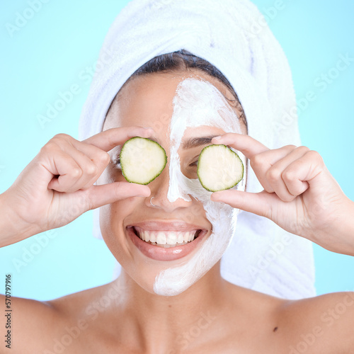 Beauty, cucumber and skincare face mask on a woman with vegetable slice for dermatology cosmetics. Aesthetic model person with spa facial for self care, skin glow and wellness on blue background