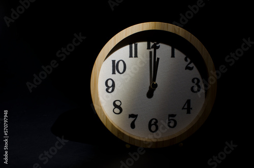 Wooden clock showing 12 o'clock in the darkness.