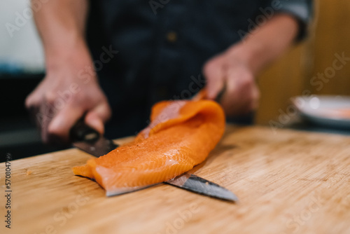 Ein Stück Fisch wird von einem Koch filetiert (ID: 570804729)