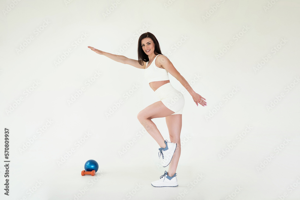 happy sports girl in a white suit goes in for sports. portrait of a sports girl in full growth on a gray background, looking into the camera.