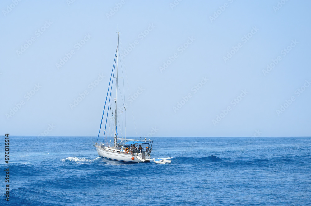 A yacht in the open sea overcomes the waves against the blue sky. Sea trips on a yacht.