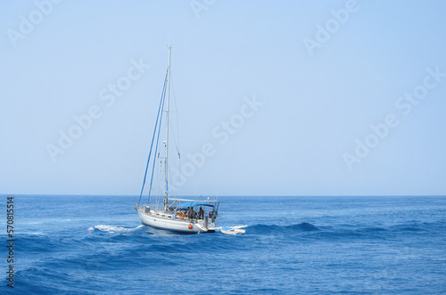 A yacht in the open sea overcomes the waves against the blue sky. Sea trips on a yacht.