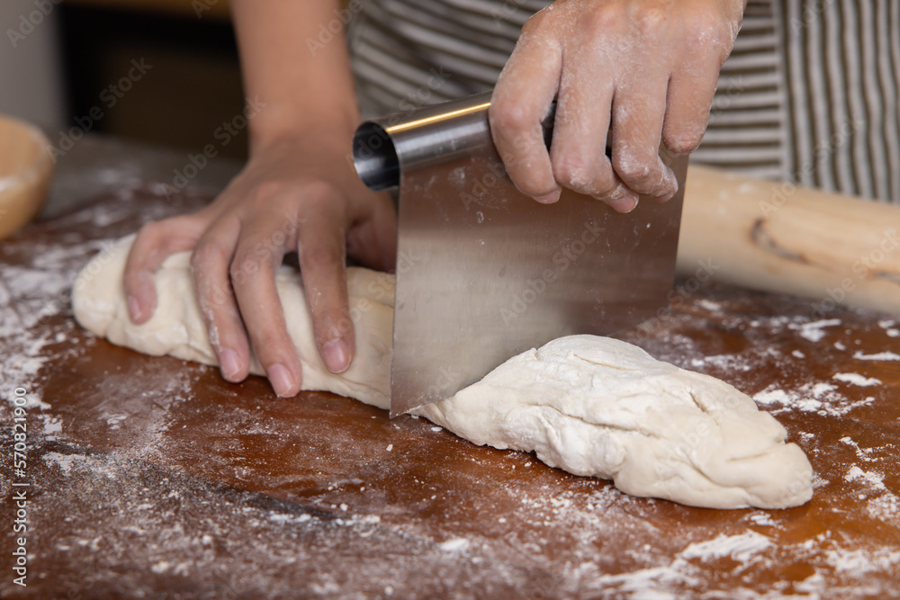 Baker Hand Cutting Raw Dough with a Knife